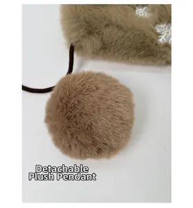 Détail d'un sac en peluche marron avec broderie flocon et pompon en fourrure amovible