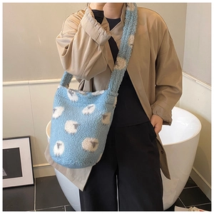 Détail de la texture en peluche bleu clair et des motifs de moutons blancs sur le sac