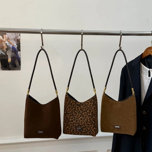 Detailed close-up of three suede hobo bags in dark brown, leopard print, and light tan colors