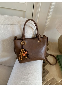 Detailed view of retro brown crossbody bag with colorful beads on a white sofa backdrop