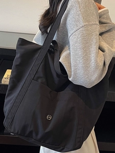 Large capacity black nylon tote bag for women showing practical shoulder carry and sleek logo