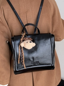 Vintage glossy black mini backpack for women featuring a cute plush bear charm and ilm logo