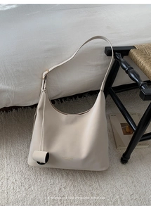 Close-up of creamy white leather tote bag featuring elegant gold embossed lettering details