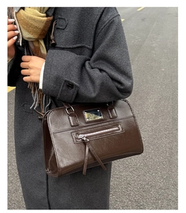 Close-up of vintage brown tote bag with metal plaque and tassel in autumn setting
