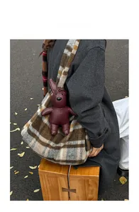 Detail showing high-capacity checkered tote bag with a decorative faux leather rabbit charm