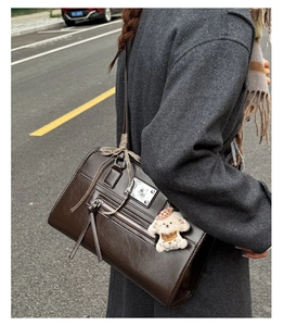 Macro detail of coffee brown PU leather bag with tassel zipper and puppy charm