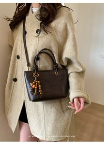 Detail of vintage brown bucket bag with bead pendant and minimalist brand embossing