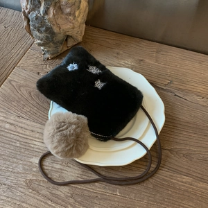 Gros plan du sac à bandoulière en peluche noire avec broderie de flocon et pompon doux