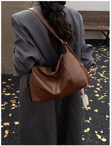 Detail of vintage brown leather tote bag with wide strap and side stitching texture