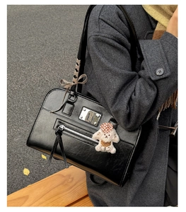 Detail of black leather handbag with long tassels, silk ribbon, and cute puppy charm