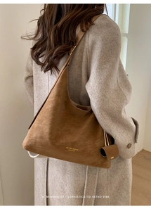 Side view of large brown leather tote bag with small pouch charm on a female model