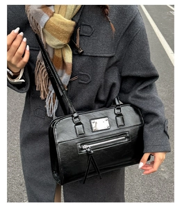 Detail of vintage black leather tote bag with silver hardware on a winter coat