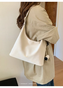Detailed side view of a large cream leather tote bag shown on a model for daily commute