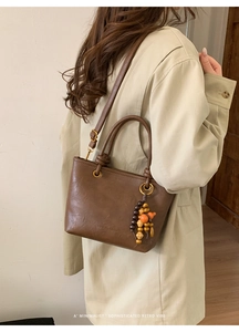 Detail of vintage dark brown leather bucket bag with tassel and fashion engraving