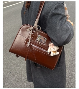 Detailed outdoor shot of a vintage brown handbag with bear pendant and metallic buckle