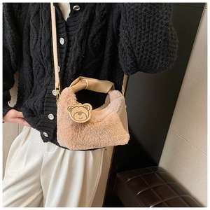 Dettaglio della borsa in peluche beige con manico in pelle e ciondolo a forma di orso