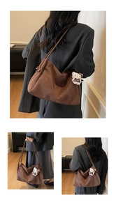 Gros plan d'un sac fourre-tout en daim mat avec logo embossé et pendentif en peluche