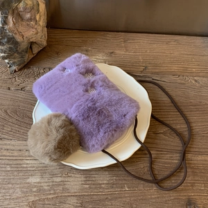 Détail d'un petit sac à bandoulière en peluche violette avec motif flocon et pompon brun