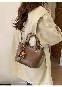 Retro coffee brown tote bag detail featuring beaded pendant and matte PU leather texture