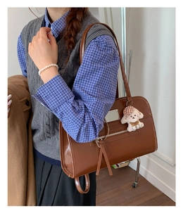 Close-up of vintage brown leather tote bag with stylish tassel and cute plush dog pendant