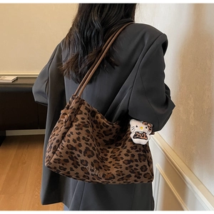 Détail d'un sac cabas imprimé léopard avec bandoulière en cuir marron et pendentif peluche