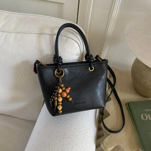 Dettaglio borsa tote nera vintage in pelle con ciondolo di perline e zucca in legno