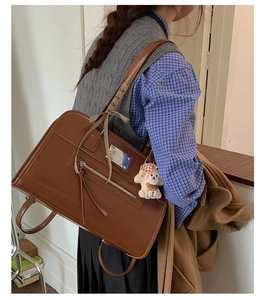 Close-up of vintage brown tote bag with metal trim, checkered bow and dog plush pendant