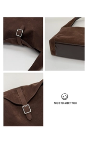 Detail view of brown suede handbag featuring silver metal buckle and reinforced leather base