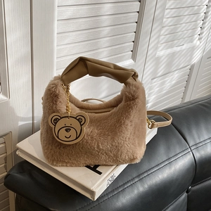 Dettaglio di borsa in peluche color cammello con manico a torsione e ciondolo orso