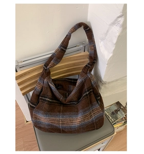 Detail of large brown plaid wool tote bag with thick textured fabric on a chair