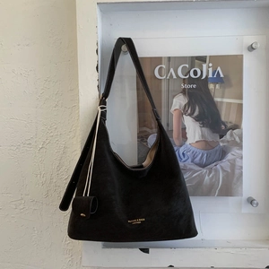 Detailed macro view of black suede tote bag with gold logo and matching mini pouch