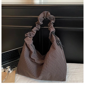 Detail of hobo bag featuring brown checkered pattern and ruched shoulder strap detail