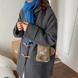 Détail d'une poche en peluche marron avec broderie de flocon de neige sur un manteau en laine