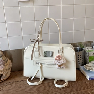 Detail of cream white leather handbag with plaid ribbon and plush dog charm