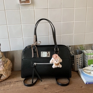 Detail of black faux leather handbag with vintage bow and cute puppy charm accessory