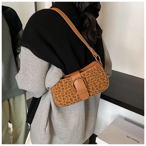 Detail of leopard print underarm bag with gold circular buckle and brown strap on model
