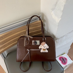 Close-up of deep brown vintage handbag featuring metal hardware and cute puppy charm