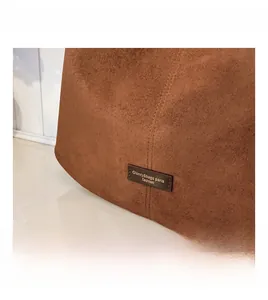 Detail of vintage brown suede bucket bag featuring contrast stitching and a leather logo tag