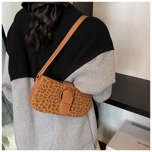 Detailed view of leopard print shoulder bag with large metal buckle on textured fabric