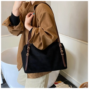 Detailed close-up of suede texture on a black tote bag with brown leather straps