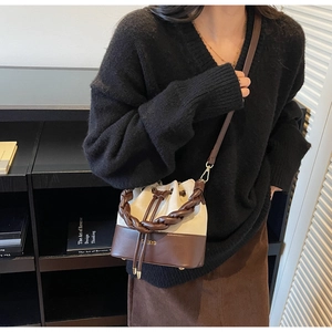 Canvas bucket bag with braided handle and leather base worn by a model in a cozy city setting