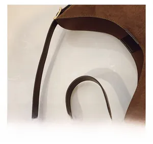 Detail view of brown suede crescent bag featuring double zip design and gold hardware