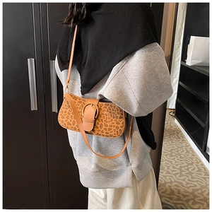 Detail of leopard print shoulder bag with large gold buckle on soft brown faux leather strap