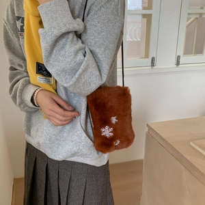 Détail d'un petit sac bandoulière en peluche marron avec broderie de flocons de neige