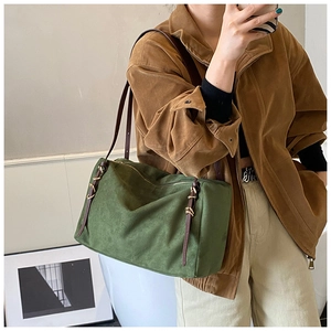 Detail of dark green suede pillow bag featuring woven leather trim and golden hardware