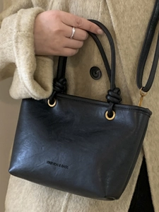 Borsa a mano nera minimalista con manico a nodo ed eleganti dettagli in oro