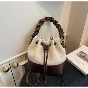 Detail of a color-block bucket bag featuring a woven handle and drawstring closure