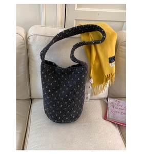 Close-up of charcoal sherpa bucket bag with white polka dots on soft fabric sofa