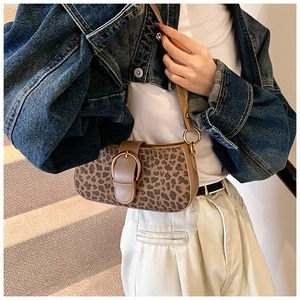 Detail of leopard print baguette bag with golden metal buckle on vintage shoulder strap