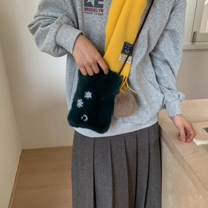 Détail du mini sac en peluche verte avec broderie flocon de neige et pompon en fourrure
